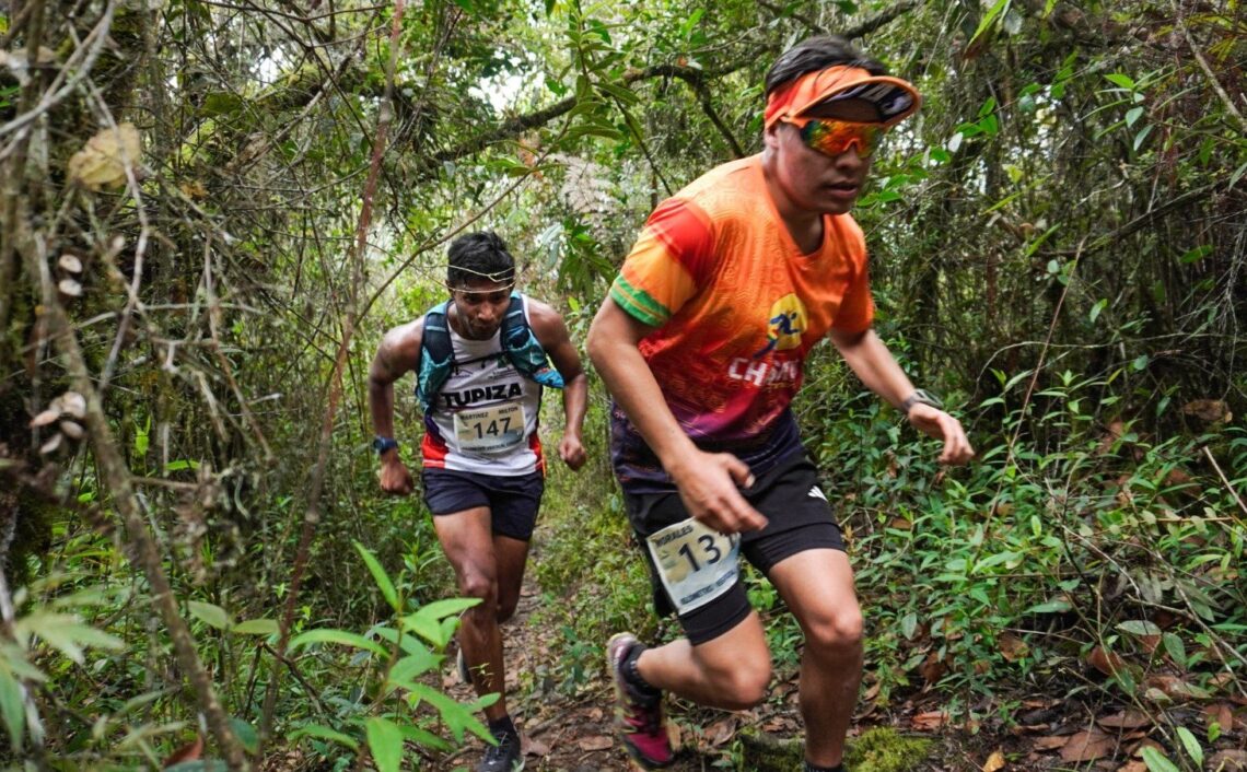 Dos atletas cruzan una zona boscosa en los yungas paceños.