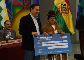 El presidente Luis Arce entrega el primer crédito a una beneficiaria.