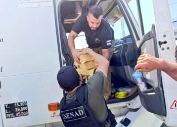 Un agente antinarcótico baja del camión la droga incautada.