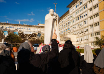Fieles católicos oran por el papa Francisco al pie de la estatua de Juan Pablo II, en Roma.
