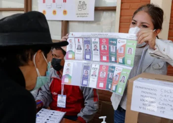 Una jurado de mesa muestra la papeleta de votación en 2020.