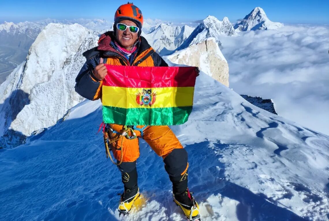 Hugo Ayaviri en la cima de la montaña, con la bandera de Bolivia.