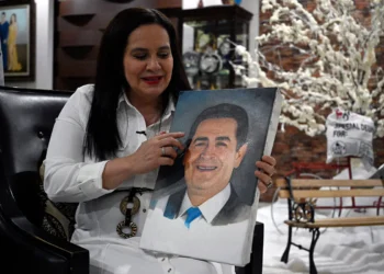 Ana García de Hernández, esposa del expresidente hondureño Juan Orlando Hernández, sostiene una pintura de su esposo. Foto: AFP